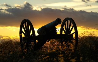 A Civil War era cannon in a field at sunset